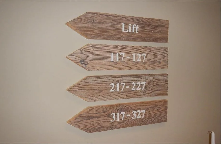 Vier gefräste Wegweiser aus Holz an einer Innenwand