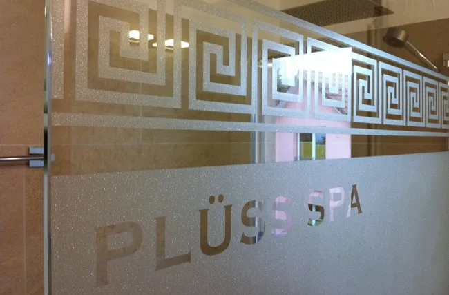 Glasdekor mit Ornamentband und ausgeschnittenem Schriftzug PLÜSS SPA