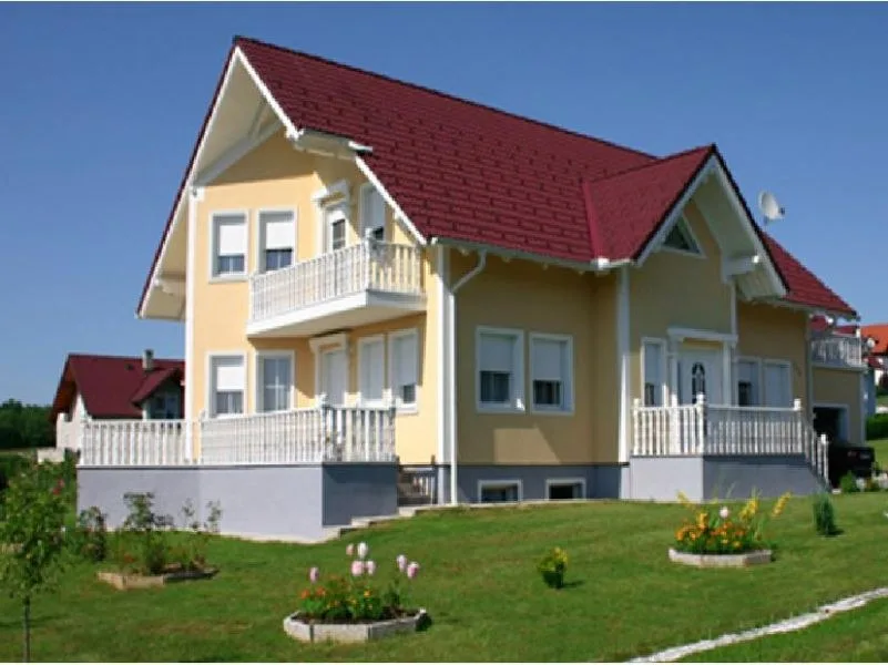 Gestrichene gelbe Wohnhausfassade mit weißen Faschen